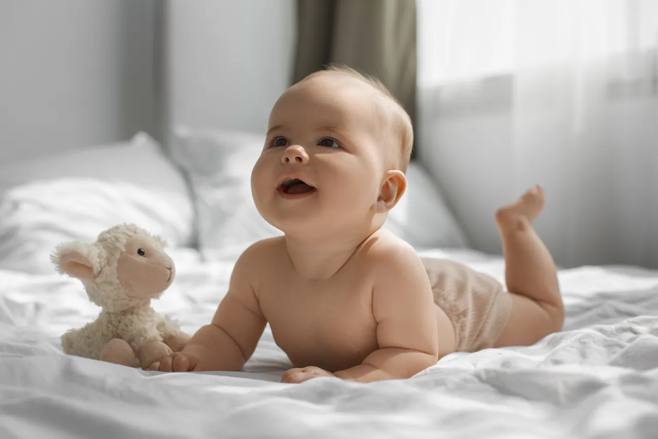 Baby lying on their tummy beside a soft toy
