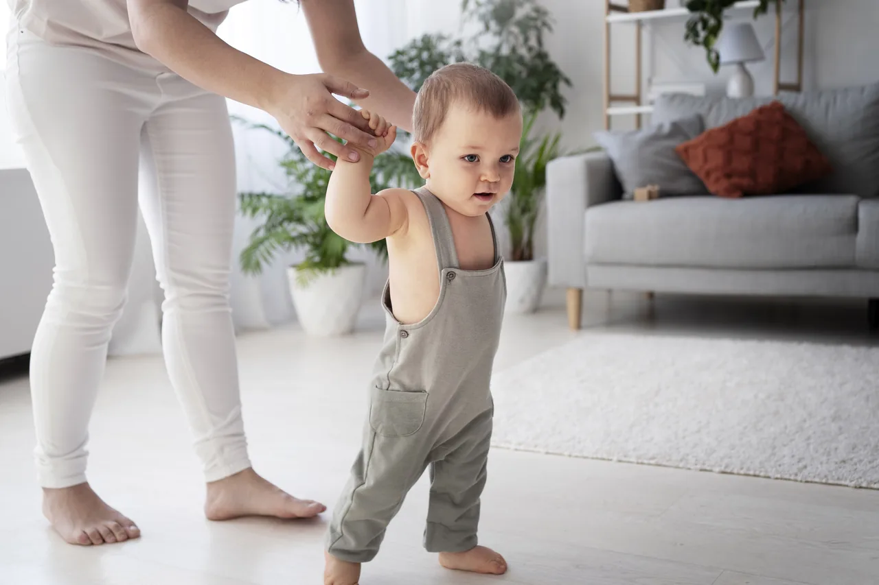 Parent holding a baby's hand as they practise their first steps at home